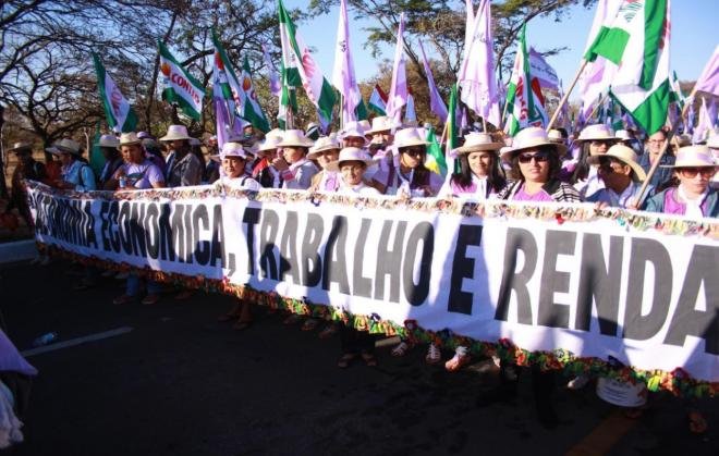 mulheres camponesas caminham em marcha em Brasília segurando faixa com os dizeres "autonomia econômica, trabalho e renda"