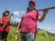 duas mulheres agricultoras familiares com enxada nas mãos cuidando da plantação