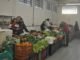 feira de alimentos da agricultura familiar com duas pessoas, um homem e uma mulher, abraçados, comercializando legumes e hostaliças